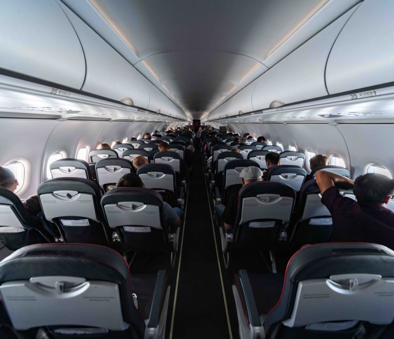 Airplane cabin seats with passengers. Economy class of new cheapest low-cost airlines without delay or cancellation of flight. Travel trip to another country.