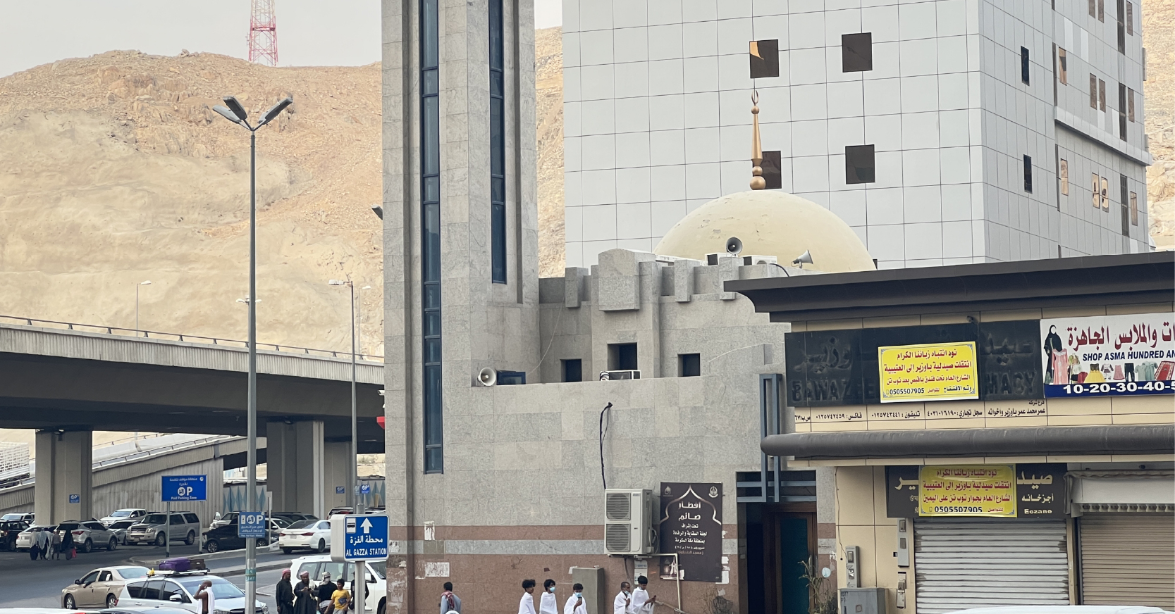 Mekke şehir merkezinde, modern binalar, dükkanlar ve bir üst geçidin yanında yer alan, kubbeli ve minareli tarihi Mescid-i Şecere yapısı.