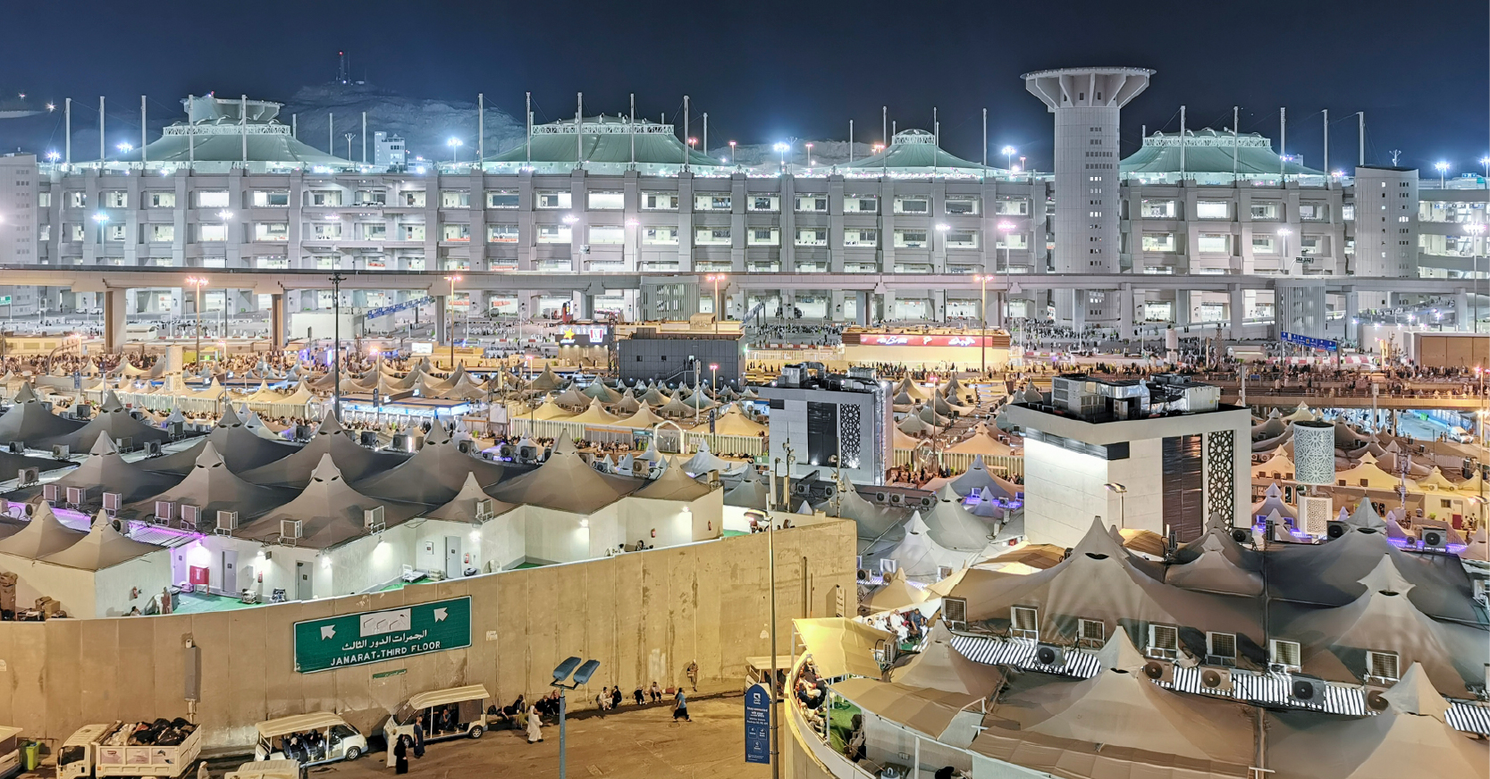 Mina'da gece vakti, aydınlatılmış çok katlı binalar ve hacıların konakladığı çadırların oluşturduğu kalabalık bir şehir manzarası.