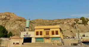 Mekke'de dağların eteğinde yer alan, sarı renkli tarihi bina görünümündeki Mekke Kütüphanesi ve Peygamberimiz'in (s.a.v.) doğduğu ev olarak bilinen alan.