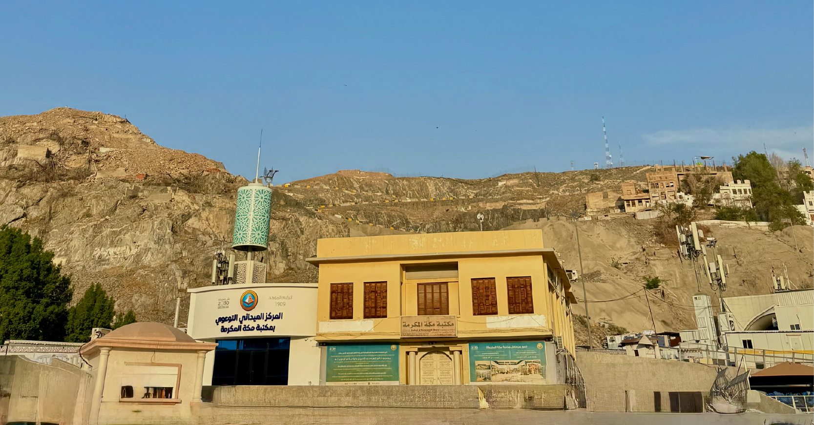 Mekke'de dağların eteğinde yer alan, sarı renkli tarihi bina görünümündeki Mekke Kütüphanesi ve Peygamberimiz'in (s.a.v.) doğduğu ev olarak bilinen alan.